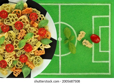 Tricolor Pasta In Form Of Football Boots, Balls And Cups On Plate Like Soccer Ball, Dish Mat Like Football Field. Italy Flag Colors In Green Basil, White Pasta And Red Cherry Tomato. Goal Concept.