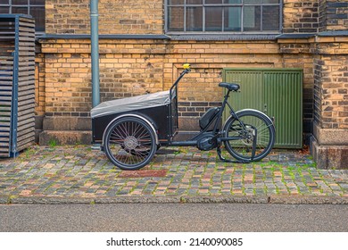 A tricycle cargo family bike with box for the transport of children stands on a street in old town. Copenhagen, Denmark - Powered by Shutterstock