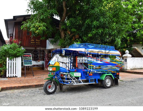 A tricycle (Tuk Tuk) parked in front of a\
restaurant in Luang Prabang,\
Laos.