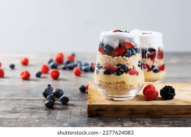 Trifle dessert with berries and cream on wooden table. Copy space