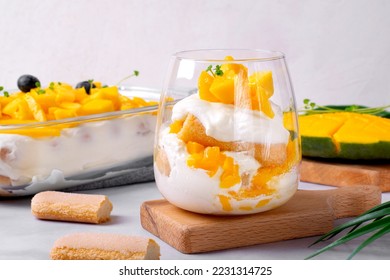 Trifle dessert with mango and ladyfinger cookies served in a glass. Tiramisu cake variation