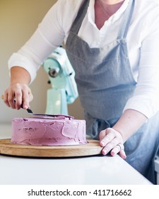 Trim The Cream Icing On A Lilac Cake With A Spatula