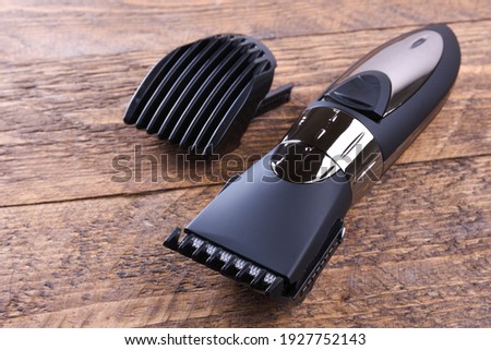Trimmer with nozzles. Buying a new wireless trimmer. On a wooden background. Close-up. With a space for text