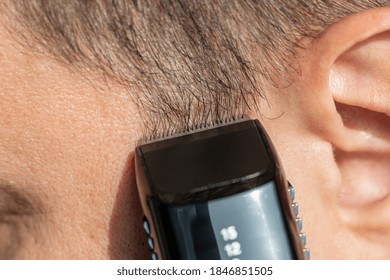 Trimming short Sideburns with clipper trimming hair. Close-up