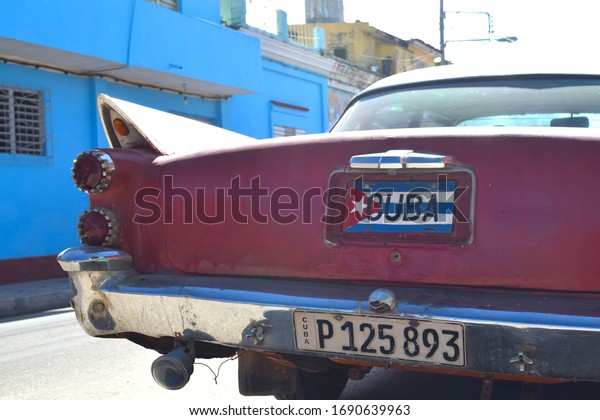 Trinidad, Cuba - December 2019: Rear of a\
Packard car with a Cuban license plate. Vintage car parked in front\
of a blue building.