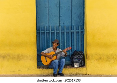 TRINIDAD, CUBA - DECEMBER 7, 2013: Man Playing The Guitar In Front Of One Of The Colonial Buildings. Cuban Music Is An Attraction For The Over 2 Million Tourists Who Go To Cuba Each Year.  