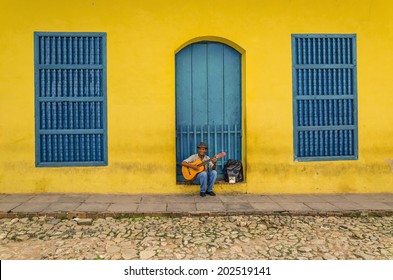 TRINIDAD, CUBA - DECEMBER 7, 2013: Man Playing The Guitar In Front Of One Of The Colonial Buildings. Cuban Music Is An Attraction For The Over 2 Million Tourists Who Go To Cuba Each Year. 