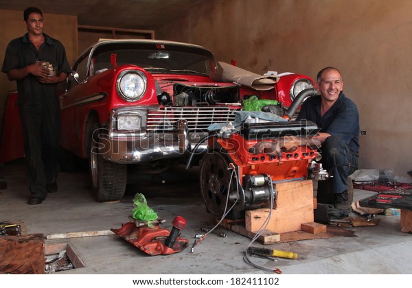 TRINIDAD, CUBA, FEBRUARY 18, 2014 : Men to\
repair classic old American car in garage. Classic cars are still\
in use in Cuba and old timers have become an iconic view and a\
worldwide known\
attraction.