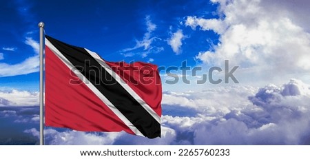 Trinidad and Tobago national flag cloth fabric waving on beautiful blue sky.