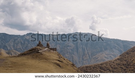 Trinity Church in Gergeti high in the mountains on a clear autumn day. Orthodox church, chapel on a hill against the background of mountains.