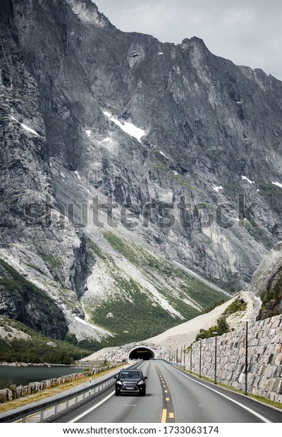 Trip to Norway.\
Lonely car rides on the norwegian road from the tunnel with\
Trollveggen mountain on background\
