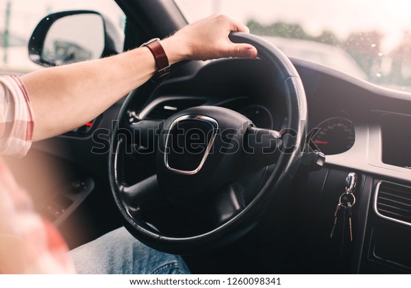trip on a modern car. The hands of the driver on\
the steering wheel.