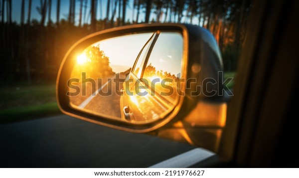 Trip sunset car mirror. Sun,\
highway car road reflection in mirror. Summer holidays trip\
concept