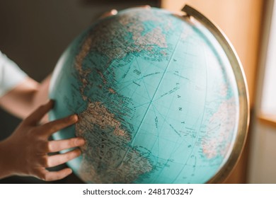 Trip and travel planning.Globe and hands close-up.childs hands twist the globe and look for countries.Countries, cities and continents on the globe.Exploring the World.  - Powered by Shutterstock