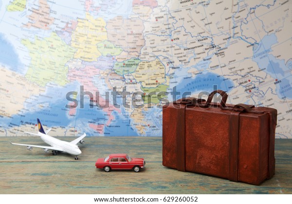 Trip or traveling by airplane concept.\
Miniature toy airplane and suitcases on\
map.