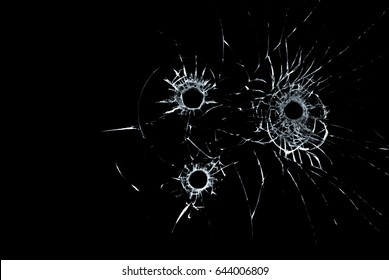 triple bullet hole in glass closeup on black background