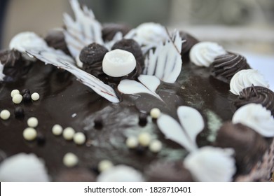 Triple Chocolate Cake Frosted On The Sides With Hand Crafted Chocolate Frosting Decorations On Tops.