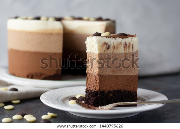 Triple chocolate mousse cake on a white plate\
with bite missing