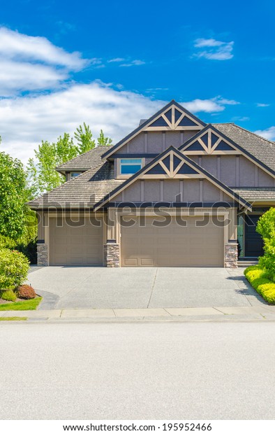 Triple\
doors garage with wide long driveway.\
Vertical.