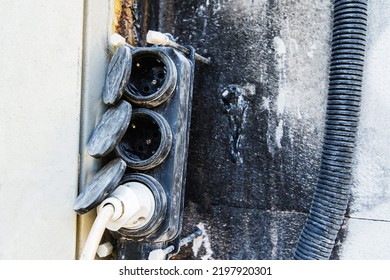 Triple Power Strip On The Background Of A Burnt Wall. Temporary Wiring After The Consequences Of A Fire. Close-up