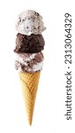 Triple scoop ice cream cone isolated on a white background. Cookies and cream, dark chocolate and heavenly hash flavors in a waffle cone.