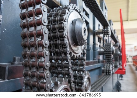 Triple strand roller chain going around three sprockets on industrial machine. Production, industry conceptual background.