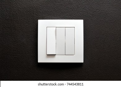 Triple Wall Light Switch On A Black Wall