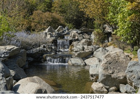 Triple waterfall in the Japanese Garden. Water falls from a height of 7 meters into artificial rocky riverbed. Close-up. Riverbed is divided into three streams, which turn into waterfalls.