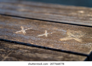 Triple X carved into a brown wooden table in the park