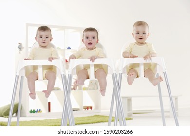 Triplet Babies Sitting In High Chairs