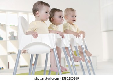 Triplet Babies Sitting In High Chairs