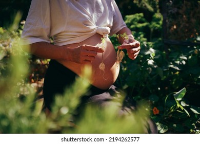 It's Triplets! Pregnant Woman In The Garden With Triplets In Her Belly, Holding Three Sprouted Plants