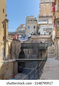 Triq Il-Lvant, Valletta, Malta - April 8th 2022: The end of the street at the Victoria Gate and the terraced arches of the Upper Barrakka Gardens in the background.
