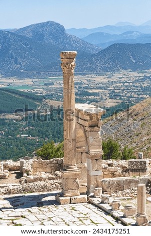 Triumphal arch and honorary column at Upper Agora in ancient city of Sagalassos. Cover page, top view. Scenic mountains of Pisidia at background. Cover page. Aglasun, Budur, Turkey (Turkiye)