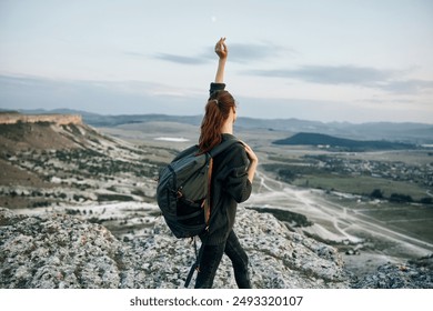 Triumphant hiker celebrating success on mountain summit with arms raised - Powered by Shutterstock