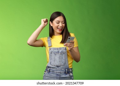 Triumphing cute joyful asian girl hold smartphone, fist pump celebrating good news, read good news message, look telephone screen smiling happily, achieve success got persmission party - Powered by Shutterstock