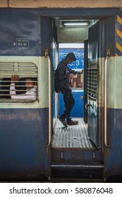 Trivandrum, Kerala, January 2 2017; Young Man Watching The Screen Of His Smart Phone While Standing On The Balcony On An Indian Railways Train. 