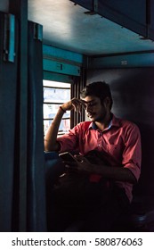 Trivandrum, Kerala, January 2 2017; Young Man Watching The Screen Of His Smart Phone While Seated In A Window Seat On An Indian Railways Train. 