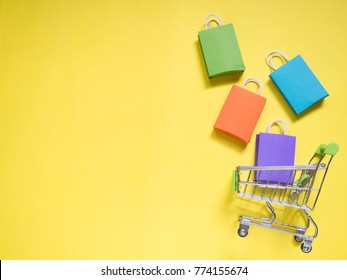 Trolley cart and colorful paper shopping bags on yellow background. Creative idea for shopping online, summer sale, supermarket, discount promotion and Black Friday concept. Copy space for text. - Powered by Shutterstock