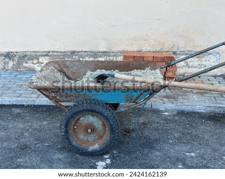 Trolley filled with sand. Shovel with sand on an old handcart