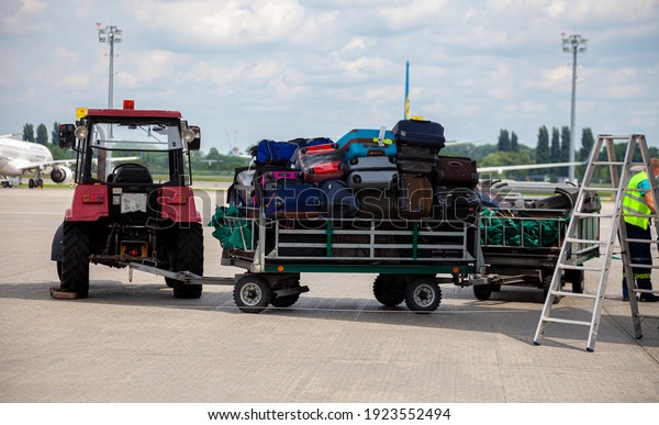 Trolley with luggage at the airport on the\
platform near the plane. Travelers\' suitcases. Passenger suitcase.\
Mini tractor special\
equipment.