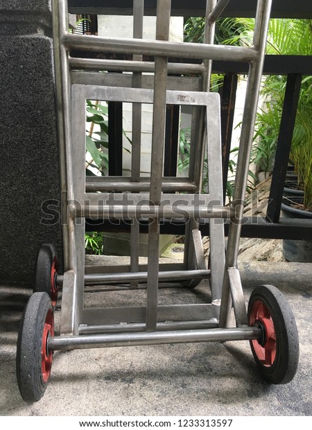 Trolley for luggage\
at the hotel resort. Empty shopping trolley, side view, Luggage\
Cart parking on cement\
floor.