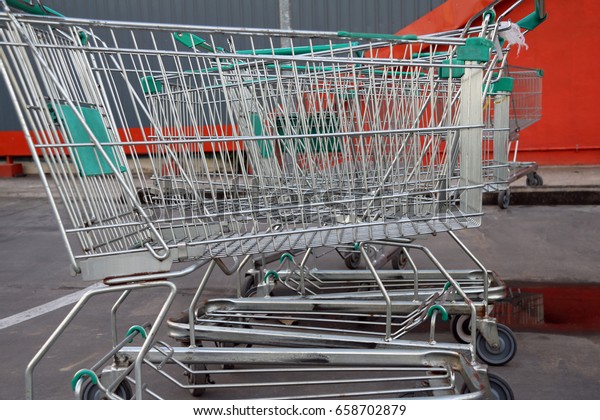 Trolley of the mall on the car park\
and the green handle of metal barrow on orange\
background.