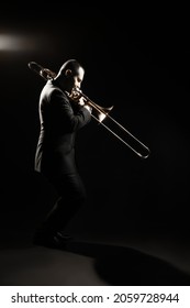 Trombone Player. Trombonist Playing Jazz Musician. Man Playing Trumpet Brass Instrument Isolated On Black Full Length Profile Portrait