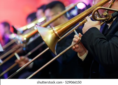 A Trombone Section Playing Together In A Traditional Big Band Jazz Ensemble. Selective Focus On The Foreground Trombone.