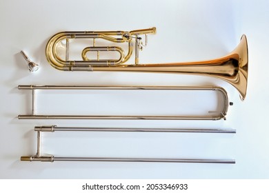 Trombone with transposer disassembled on a white table. Top view. Horizontal composition.