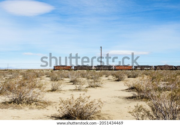 TRONA, UNITED STATES - Feb 10, 2018: Loaded\
freight train cars in peaceful desert setting of Searles Valley\
near Trona, California