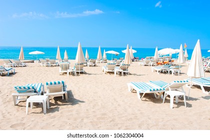 Tropical beach of Alanya. Sun beds and deckchairs on sandy sea beach on sunny, sunny day. Summer vacation concept. Tropical beach