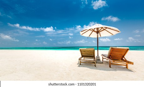 Tropical beach background as summer landscape with lounge chairs and white sand and calm sea for beach banner. Perfect beach scene - vacation and summer holiday concept. Boost up color process