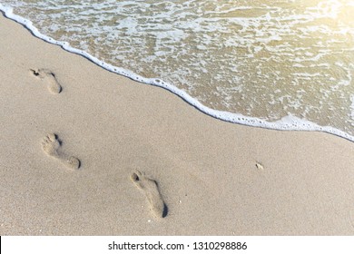 tropical beach, blue sea and white sand with traces of bare feet on it.